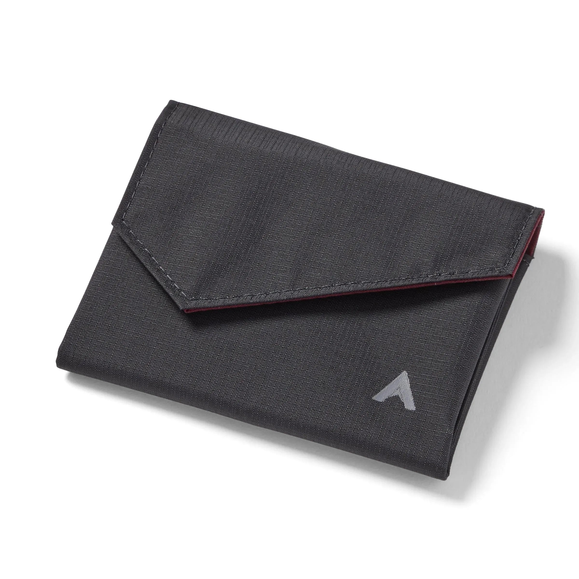 Allett's closed jet black nylon accordion wallet on a white backdrop, showcasing the logo on the bottom right and a front flap with an angled, slightly triangular shape. Allett Accordion Wallet in RFID Blocking Nylon jet-black