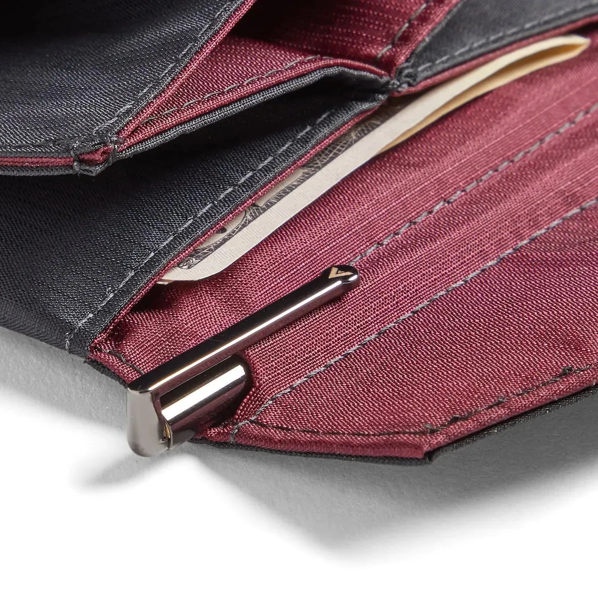 Photo is a closeup of the Micro pen that fits inside of an Allett wallet in a specific pocket that is made for the wallet. The pen is gunmetal color and the wallet is a maroon color.