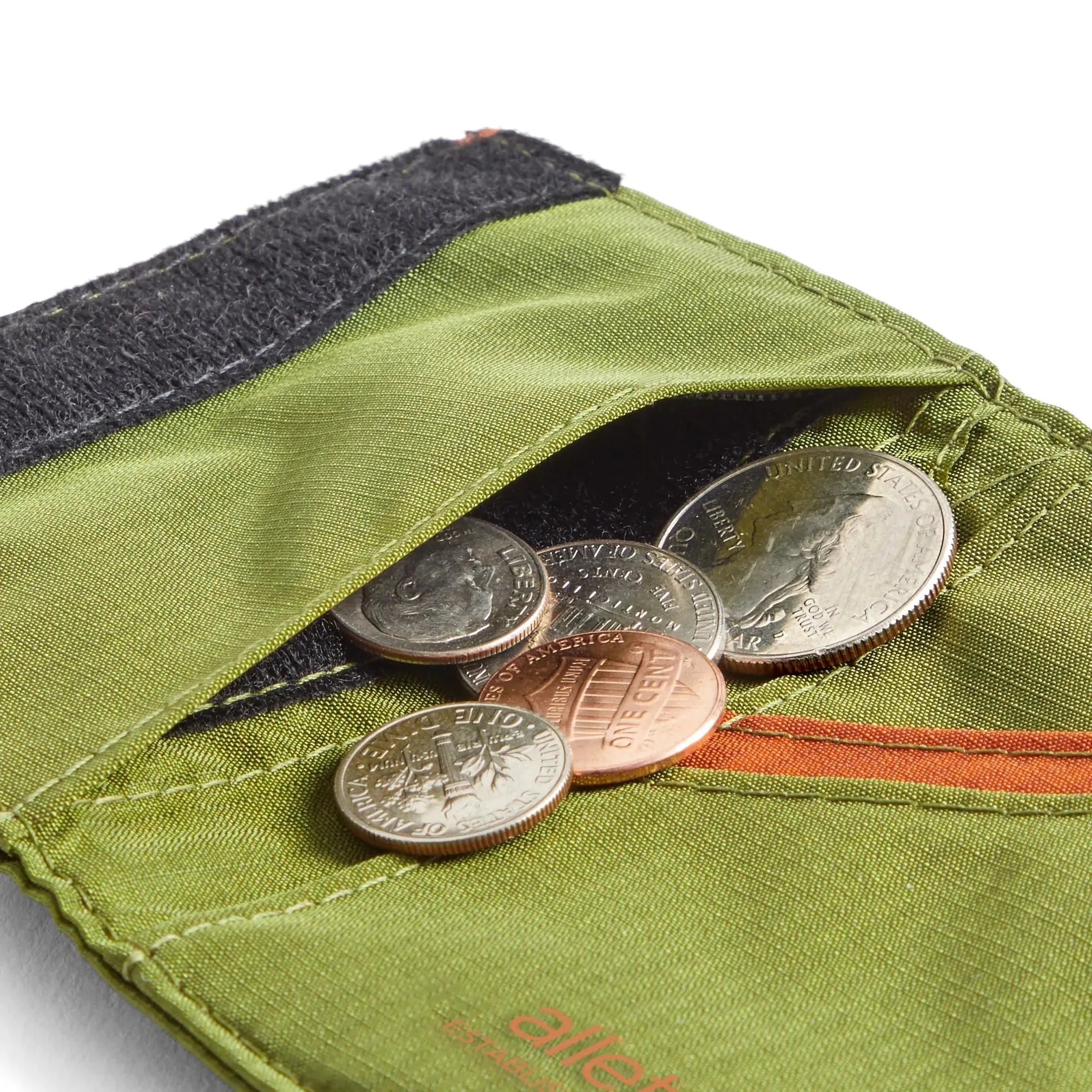 Coins emerging from the built-in coin pocket beneath the velcro side pocket of Allett's trifold wallet in cala green. allett trifold wallet cala-green