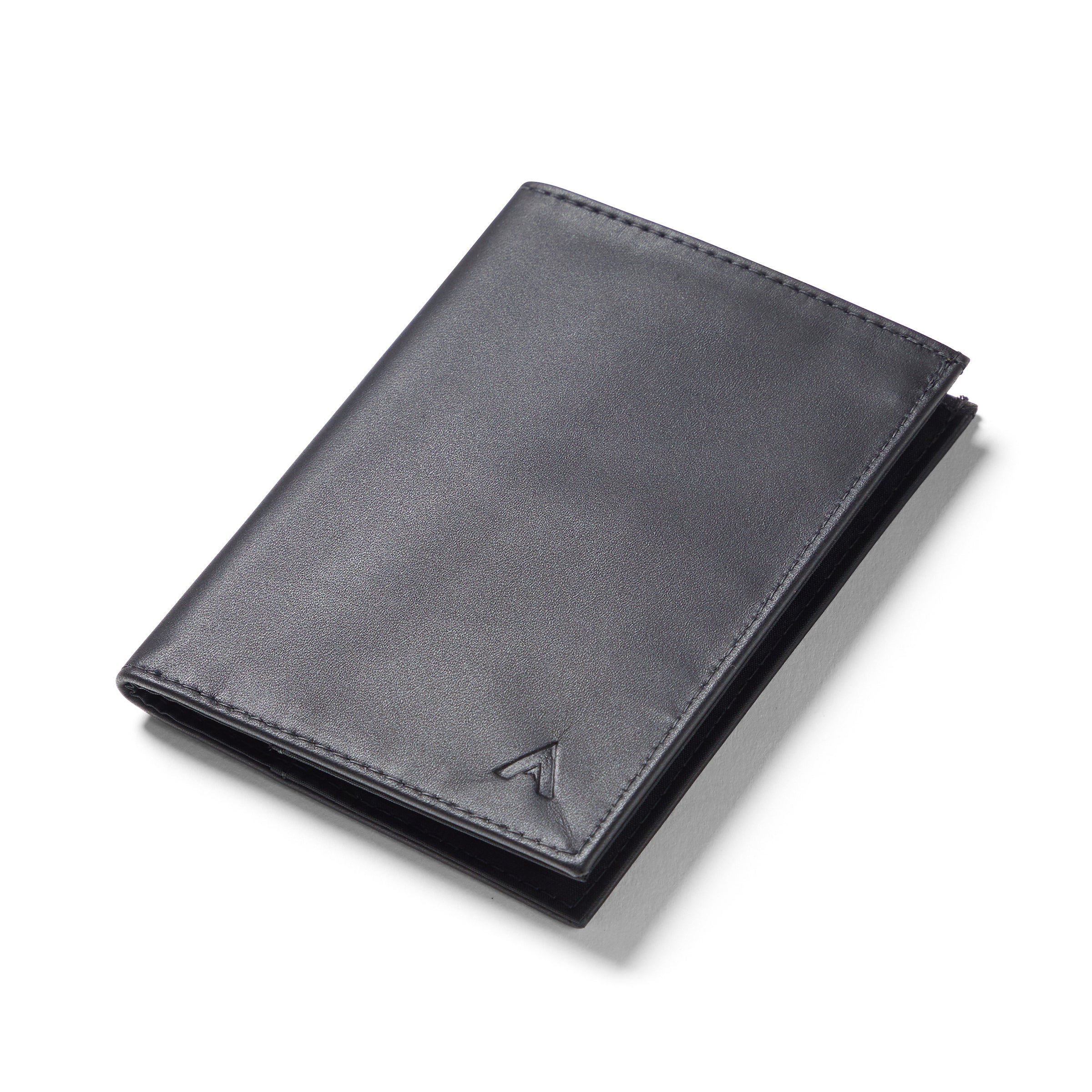 Black leather wallet designed for passports laying flat against a table - black