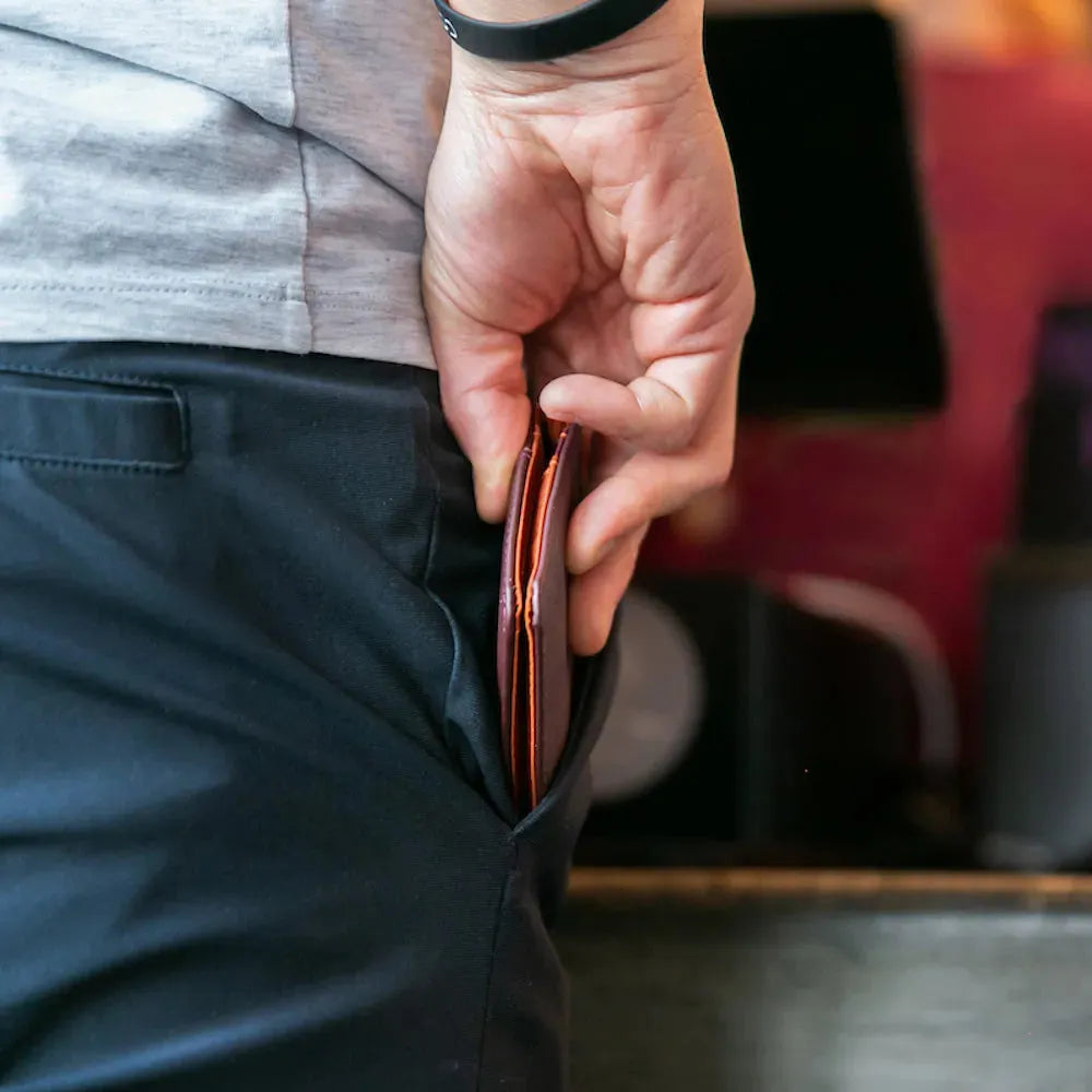 Person placing a hybrid leather card wallet form Allett in their jeans pocket. Allett hybrid card wallet leather merlot 