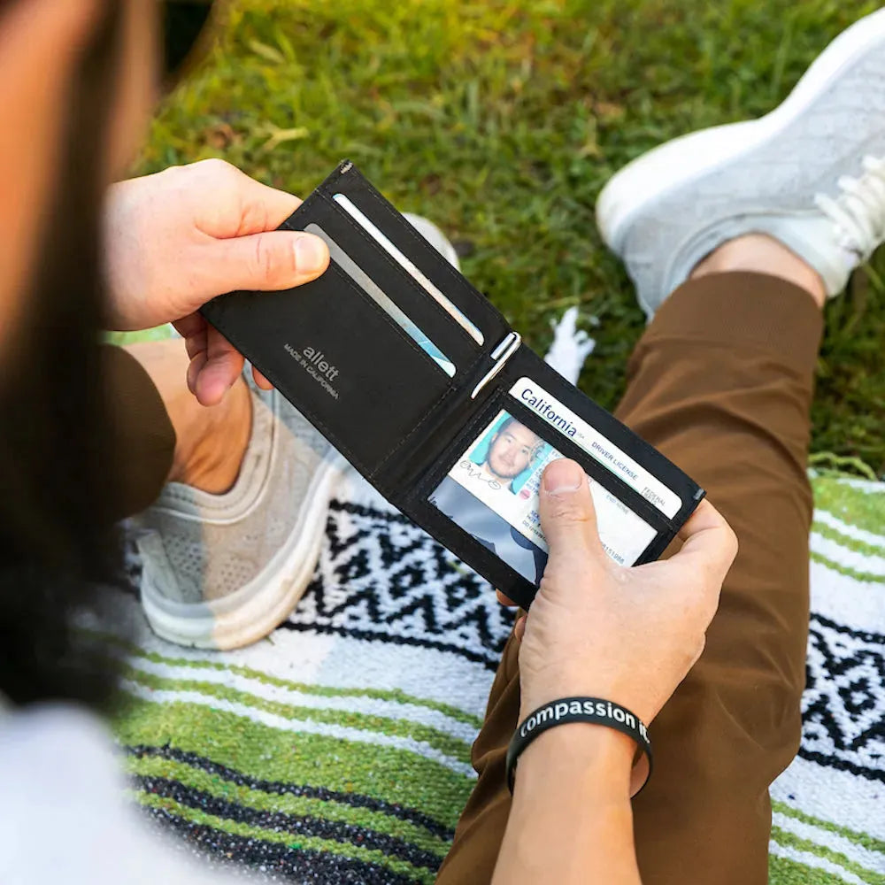 Person holding a jet black nylon ID wallet and looking at their California state ID through the clear ID cover -  Allett ID Wallet Nylon RFID jet-black